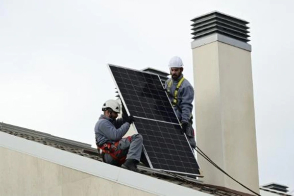 Empleados de la compañía Engel Solar sostienen un pael durante su instalación en una vivienda de Boadilla del Monte, cerca de Madrid, el 21 de diciembre de 2022