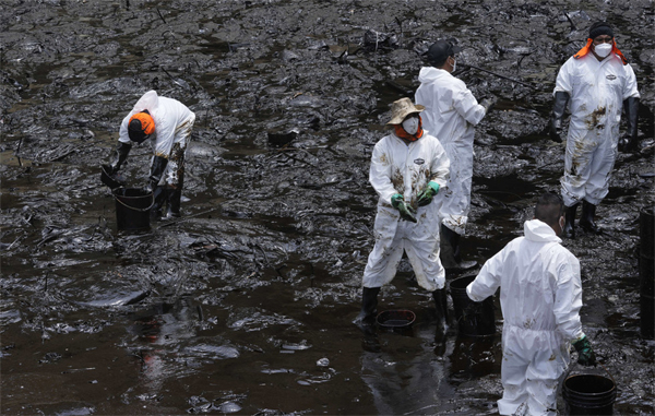 Trabajadores limpian petróleo de la playa Cavero en Ventanilla, Callao, Perú, 21 de enero de 2022 (Martin Mejia / AP)