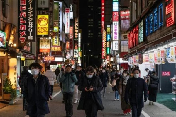 Personas caminan entre rótulos luminosos en el centro de Tokio, Japón, el 10 de enero de 2023