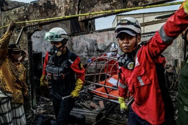 Los bomberos sacan en camilla un cadáver de los escombros de una casa devastada por el incendio de un depósito de combustible, el 4 de marzo de 2023 en Yakarta