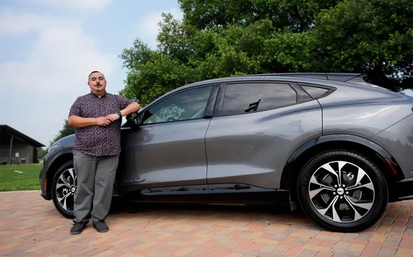 Jose Valdez, de 45 años, propietario de tres vehículos eléctricos, posa con su Mustang Mach-E, el jueves 9 de mayo de 2024, en San Antonio. Muchos estadounidenses aún no se deciden a comprar un coche eléctrico. Los altos precios y la falta de estaciones de carga fáciles de encontrar son los principales puntos de fricción, según una nueva encuesta. Valdez tiene tres coches eléctricos, entre ellos un Mustang Mach-E nuevo. Con la desgravación fiscal y otros incentivos, el nuevo y elegante coche cuesta unos 49.000 dólares. En su opinión, merece la pena. (AP Photo/Eric Gay)