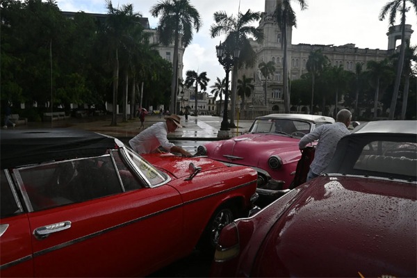 Luis Manuel Pérez, de 57 años (con sombrero), espera frente al Parque Central de La Habana junto a otros conductores, a veces durante horas, con la esperanza de que un turista lo contrate para dar un paseo en coche clásico por la capital cubana.Credit...Jorge Luis Baños para The New York Times