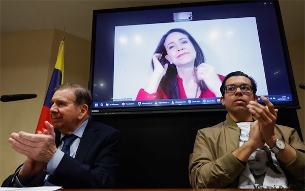 El presidente electo de Venezuela, temporalmente exiliado en España, Edmundo González y Adrián Quiñones, aplauden a la principal líder opositora venezolana María Corina Machado, que habla por videoconferencia desde Venezuela, en Madrid, España, 10 de diciembre de 2024. REUTERS/Juan Medina Comprar derechos de licencia