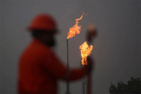 A worker takes measurements in front of gas flares at the state energy company Petroleos Mexicanos (Pemex) Perdiz Plant