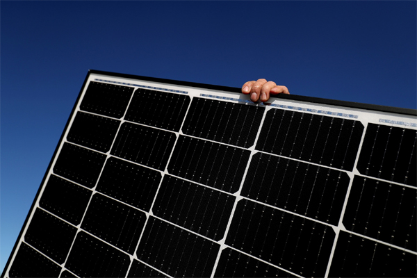 A person holds onto a solar panel  before installing on a residential rooftop. 