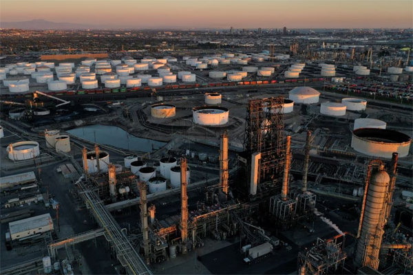 A view of the Phillips 66 Company's Los Angeles Refinery (foreground), which processes domestic & imported crude oil into gasoline, aviation and diesel fuels, and storage tanks for refined petroleum products at the Kinder Morgan Carson Terminal (background), at sunset in Carson, California, U.S., March 11, 2022. REUTERS/Bing Guan