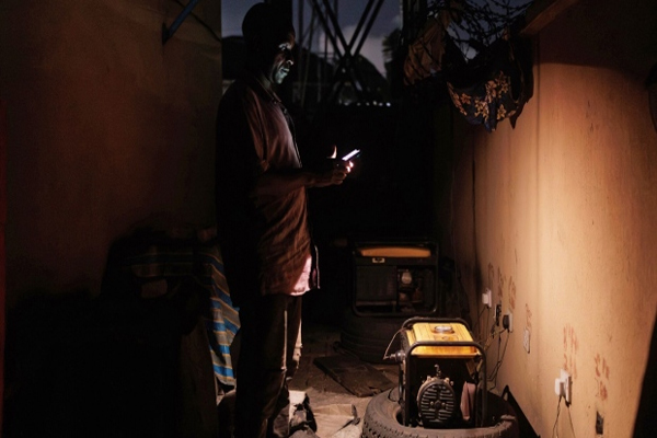 A man using his phone as a source of light trying to switch oon his generator set in Lagos, on 30 Sept, 2023 , Photographer: Benson Ibeabuchi/Bloomberg