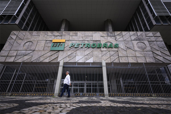 A person walks by The Petroleo Brasileiro headquarters in Rio de Janeiro, Brazil. Photographer: Buda Mendes/Getty 