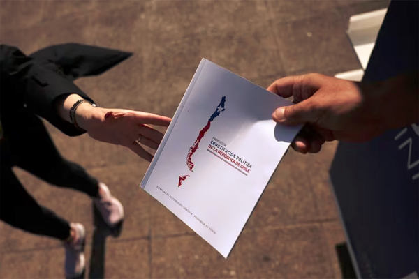 A citizen receives a copy of the proposed new Chilean constitution ahead of the upcoming December 17 constitutional referendum, outside the government palace in Santiago, Chile November 27, 2023. REUTERS/Ivan Alvarado