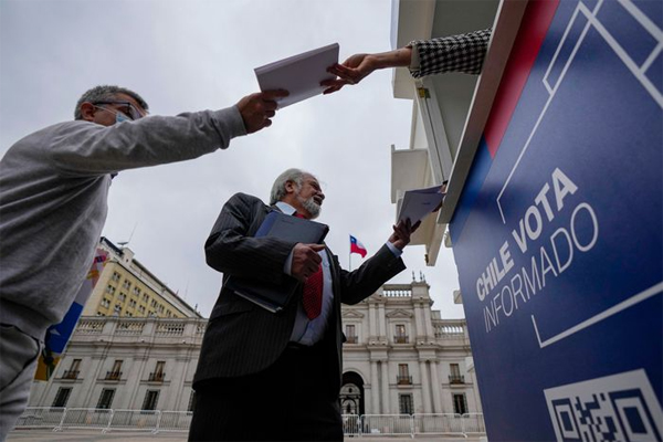 Copies of a proposed new constitution are handed out near La Moneda presidential palace in Santiago, Chile, Nov. 17. 
