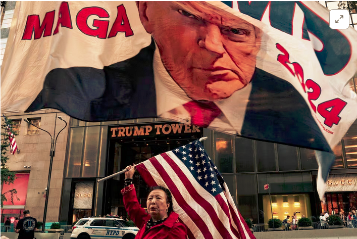 A supporter of former U.S. President Donald Trump holds up a U.S. national flag at Trump Tower in New York City, U.S., October 1, 2023. REUTERS/David 'Dee' Delgado 