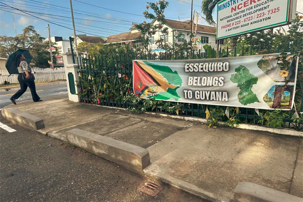 A woman passes by a banner in front of a government building in Georgetown, Guyana February 19, 2024. REUTERS/Sabrina Valle