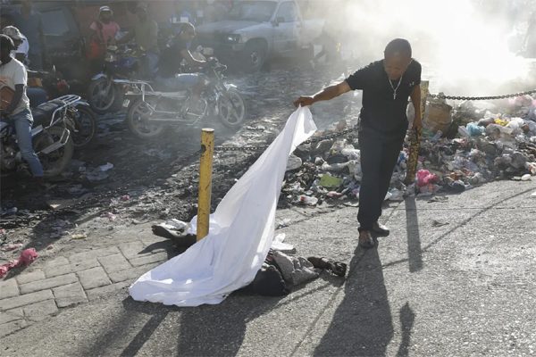 A person lifts a sheet to look at the identity of a body in Port-au-Prince, Haiti, March 18, 2024. (AP Photo/Odelyn Joseph)
